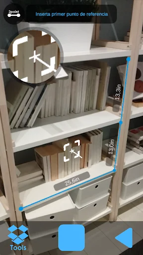 AR Meter measuring bookshelf with stored items displaying 23.6in measurement and Spanish language instructions for placing reference points in AR