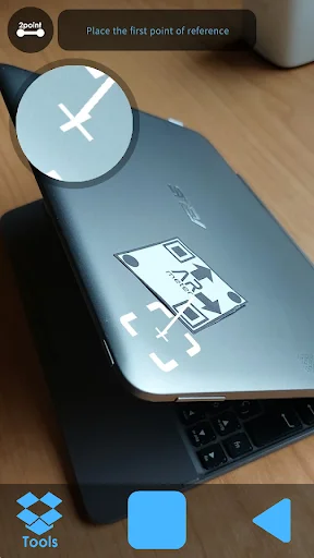 AR Meter app measuring laptop surface with crosshair placement tool and magnified reference point circle for beginning AR distance measurement